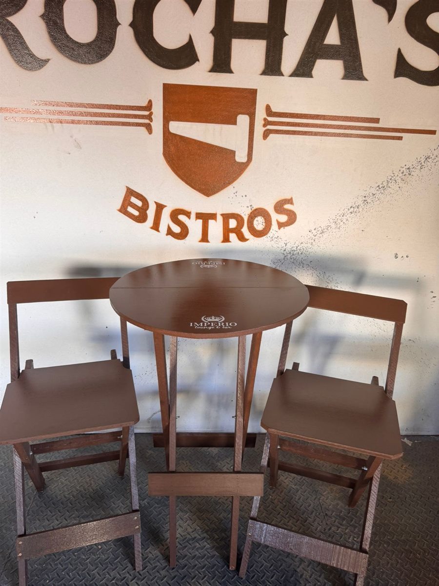 Kit bistrô de madeira com 2 cadeiras altas em frente à parede com a logo da Rocha's Bistrôs
